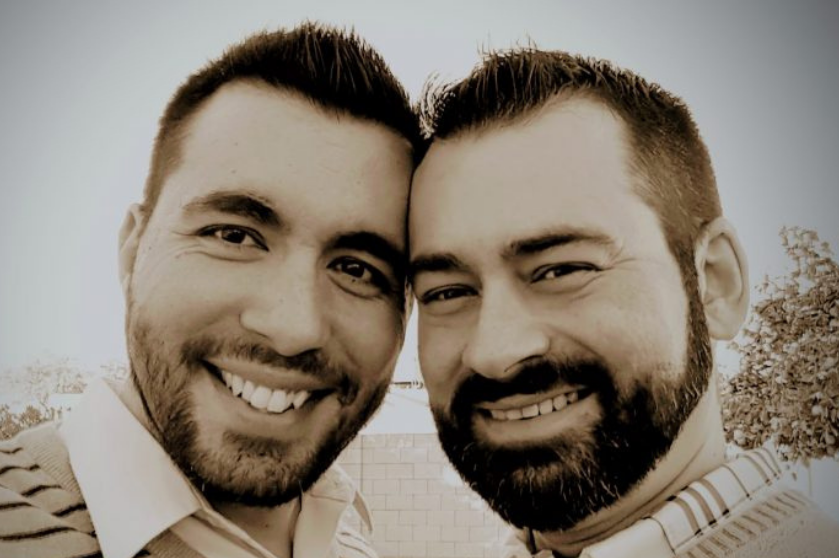 A sepia-toned portrait shows Jaime Gonzalez smiling at the camera with his husband.