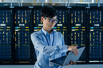 image of person opening up their computer in a data warehouse