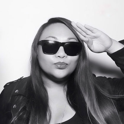 A black and white portrait shows Sheena Minoc wearing a leather jacket, sunglasses, and saluting the camera.
