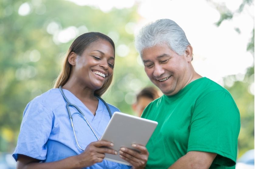 healthcare woman smiling while looking at tablet with man