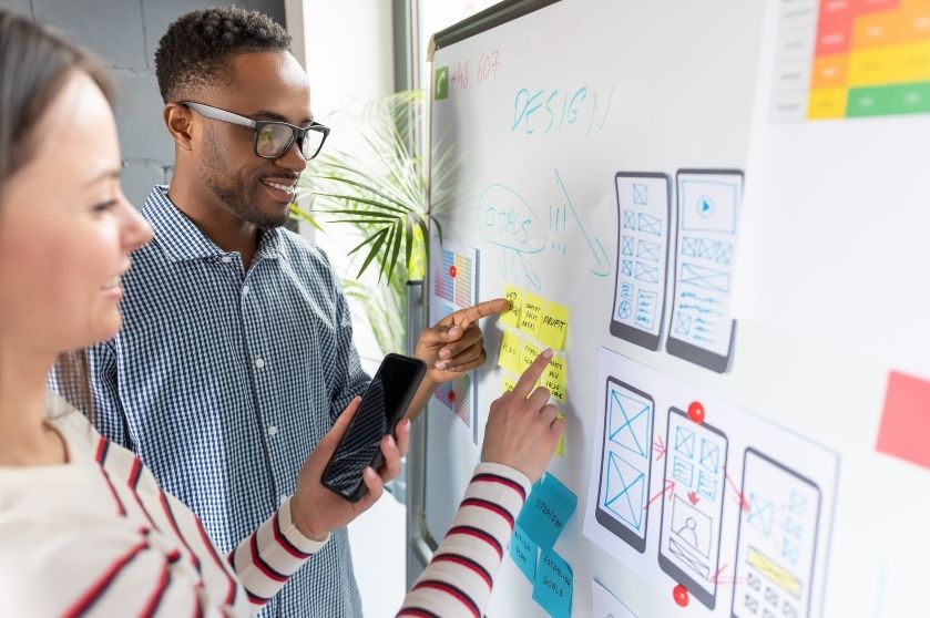 man and woman working off a whiteboard with phone interface