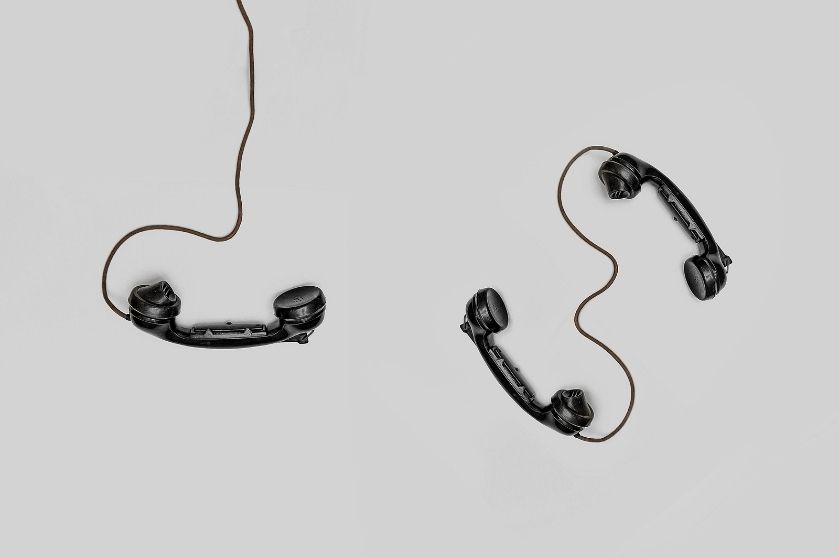 Telephones lay on a table with their cords.