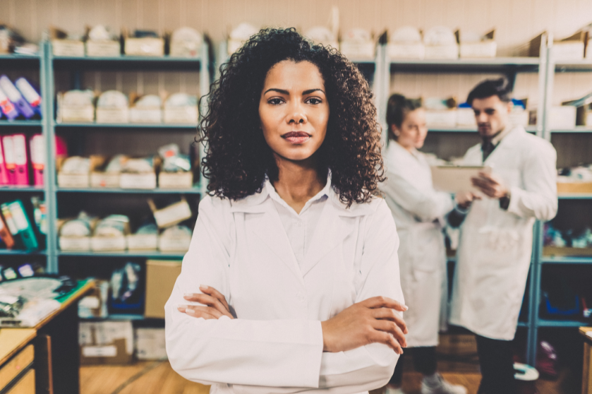 A woman stands in a lab coat.