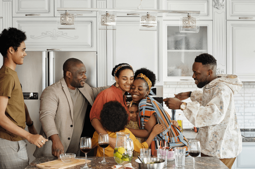 A family hugs each other in the kitchen.