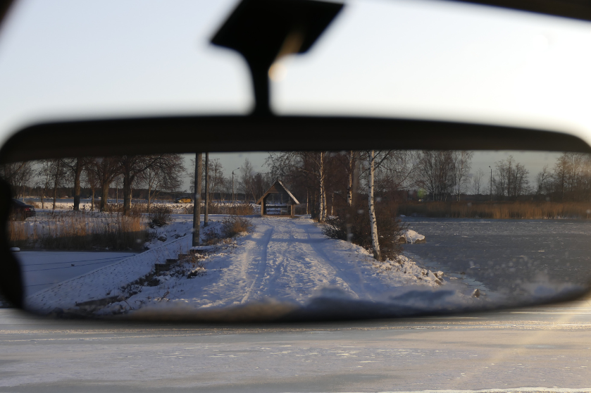 Image of road through a car rearview mirror.